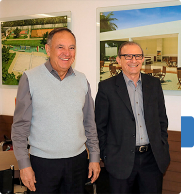 Proprietários da Imobiliária Dimensão, Dogival Corrêa e José Antônio Favarão, sorrindo no escritório